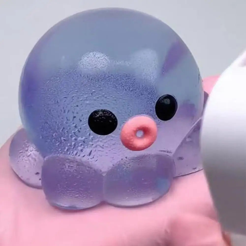 A translucent purple octopus squishy stress ball with black eyes and a pink nose is held in a hand.