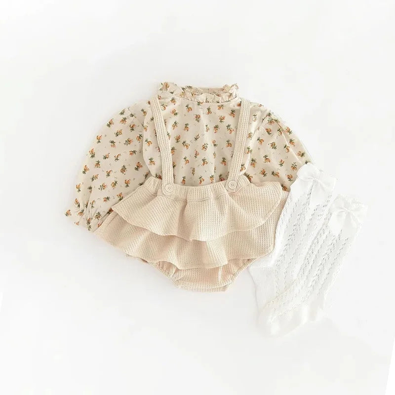 A vintage floral baby girl outfit set featuring a light-colored blouse and matching ruffled romper.