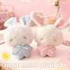 A white rabbit plush toy with blue accents and pink ears sitting on a light pink surface.