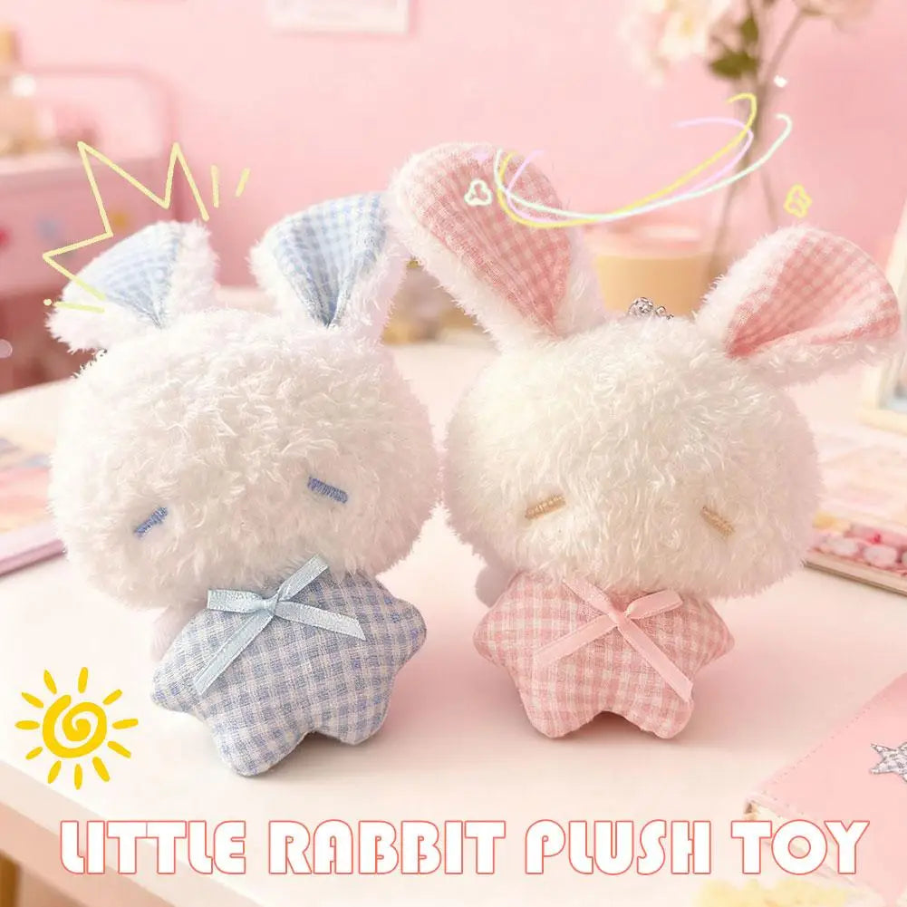 A white rabbit plush toy with blue accents and pink ears sitting on a light pink surface.