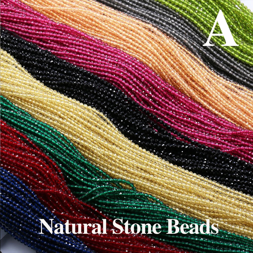 A close-up of various strands of colorful faceted natural stone beads in shades of pink, red, green, and gold.