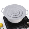 A white silicone spill stopper lid is placed on a black stovetop burner.