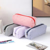 A collection of striped canvas pencil cases in red, purple, and blue, displayed on a white surface.