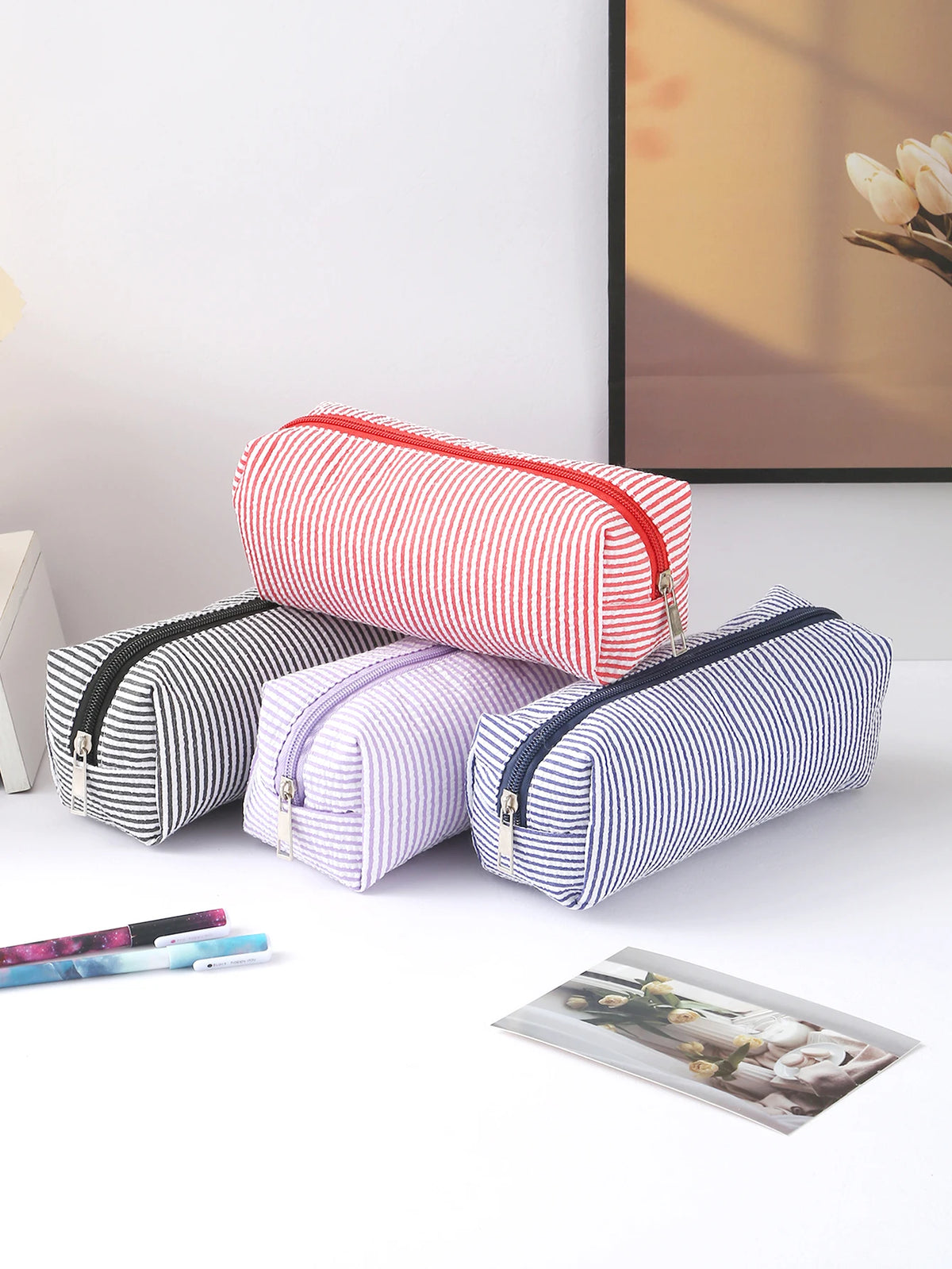 A collection of striped canvas pencil cases in red, purple, and blue, displayed on a white surface.