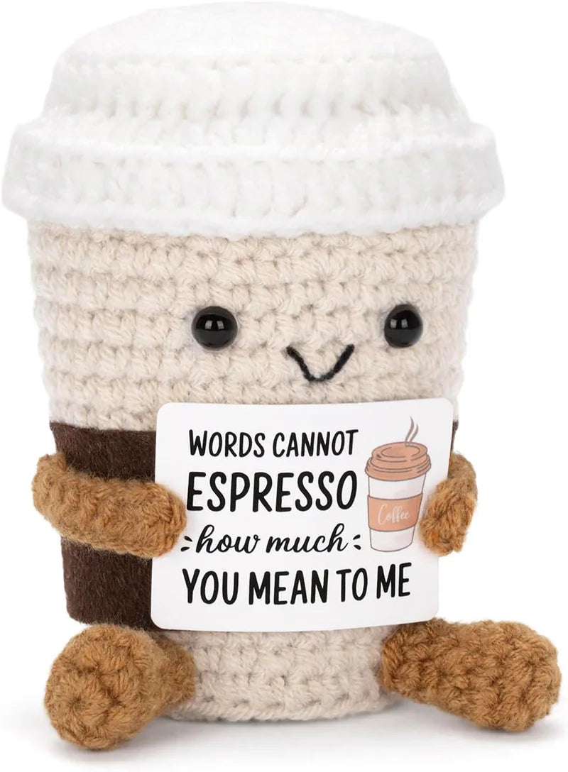 A handmade crochet plush toy resembling a cup with a positive message about espresso