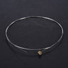 A thin, silver-colored acoustic guitar replacement string is displayed on a dark surface.