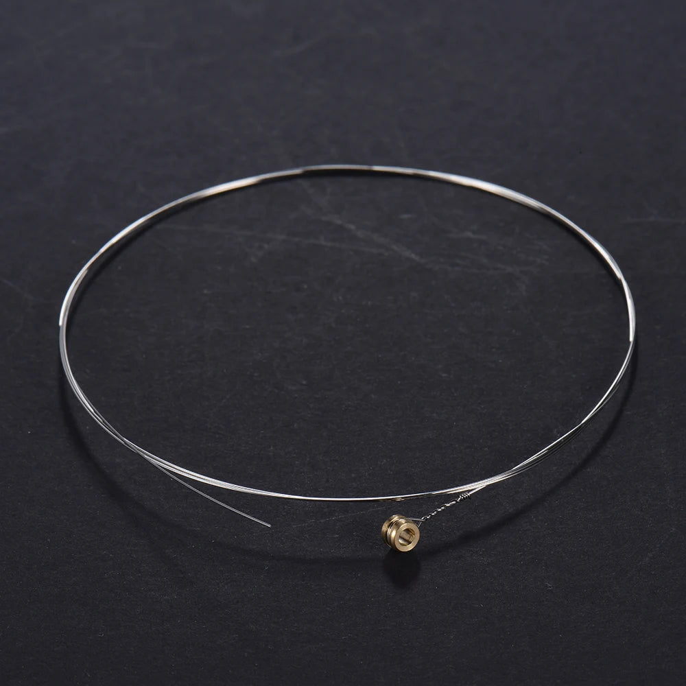 A thin, silver-colored acoustic guitar replacement string is displayed on a dark surface.