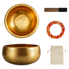 A set of handcrafted brass singing bowls, including a large bowl and a wooden mallet, with a red patterned ring and a beige c