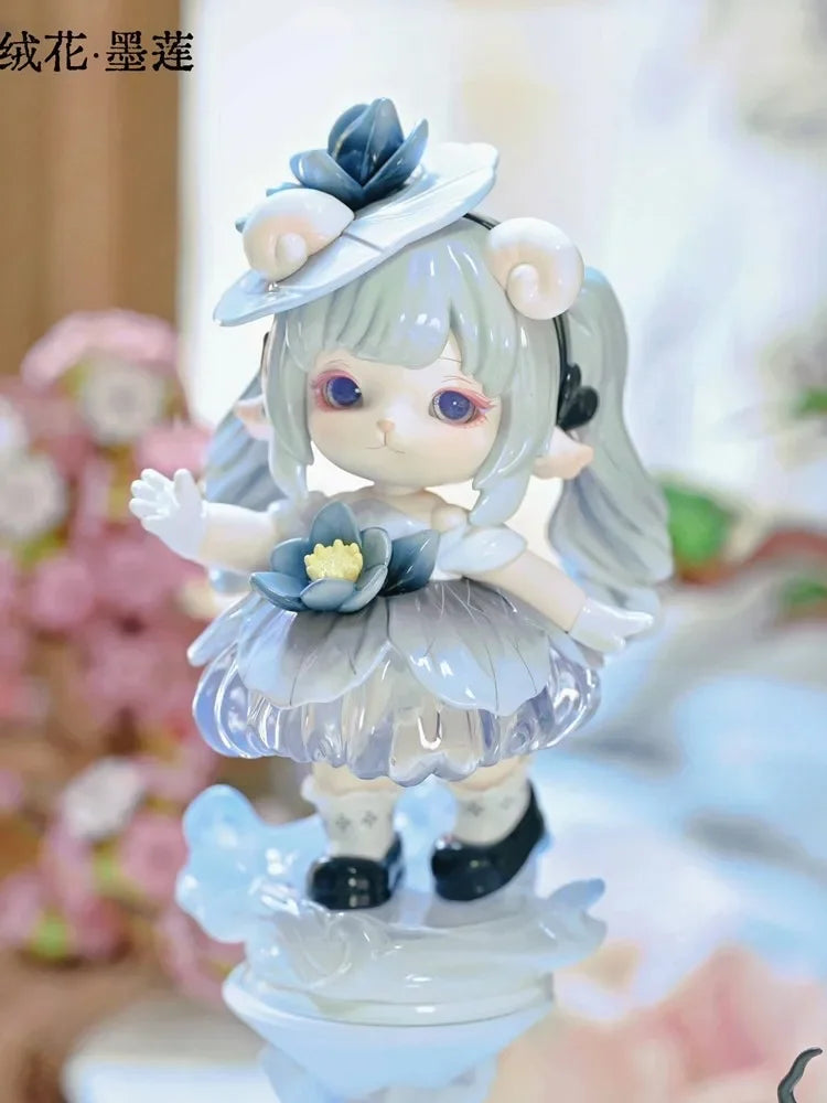 A light blue collectible figurine of a girl with silver hair and blue accents, featuring a layered dress and a wide-brimmed h