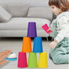 A child is playing with a set of colorful plastic stacking cups on the floor.