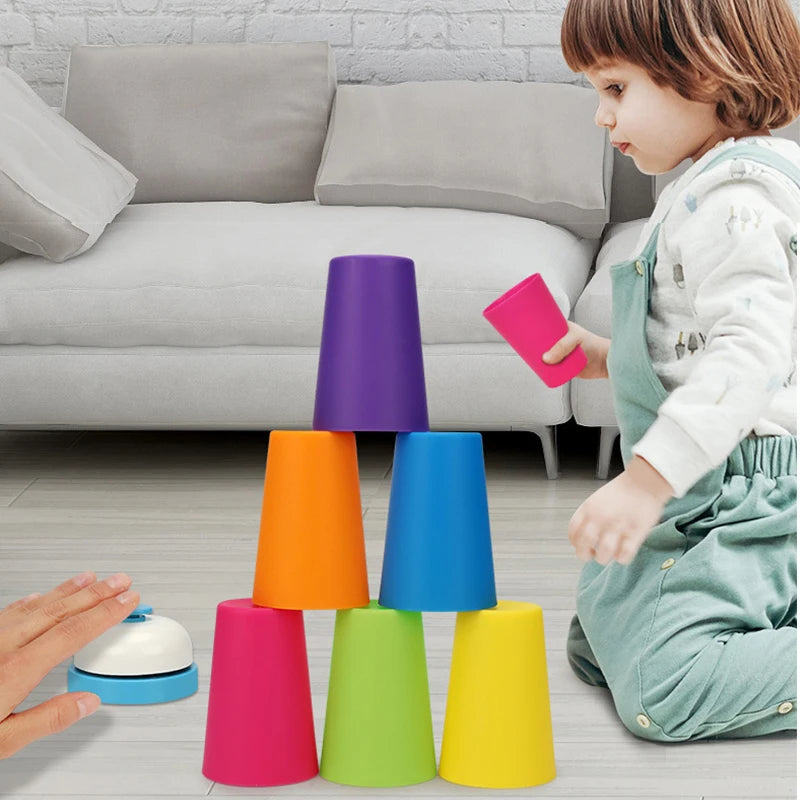 A child is playing with a set of colorful plastic stacking cups on the floor.