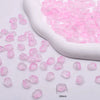 Pink gradient tulip glass beads scattered next to a white ceramic tool for jewelry making