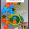 A hand holds a green net fishing toy filled with colorful, light-up bath toys for babies and toddlers.