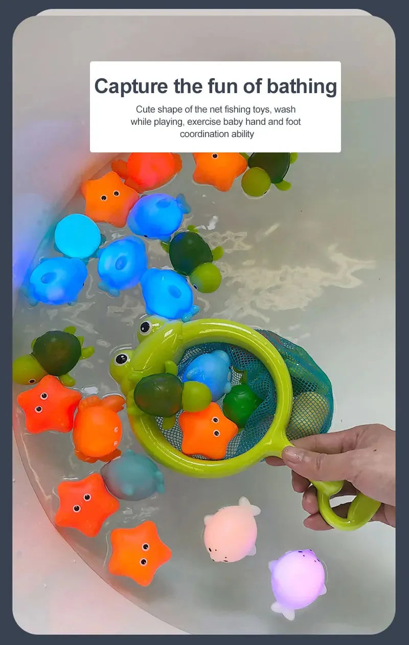 A hand holds a green net fishing toy filled with colorful, light-up bath toys for babies and toddlers.
