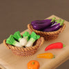 A miniature dollhouse vegetable basket play set showing various colorful bell peppers and a pumpkin in woven baskets.