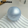 A smooth, light blue silicone fidget ball resting on a white, wavy surface.