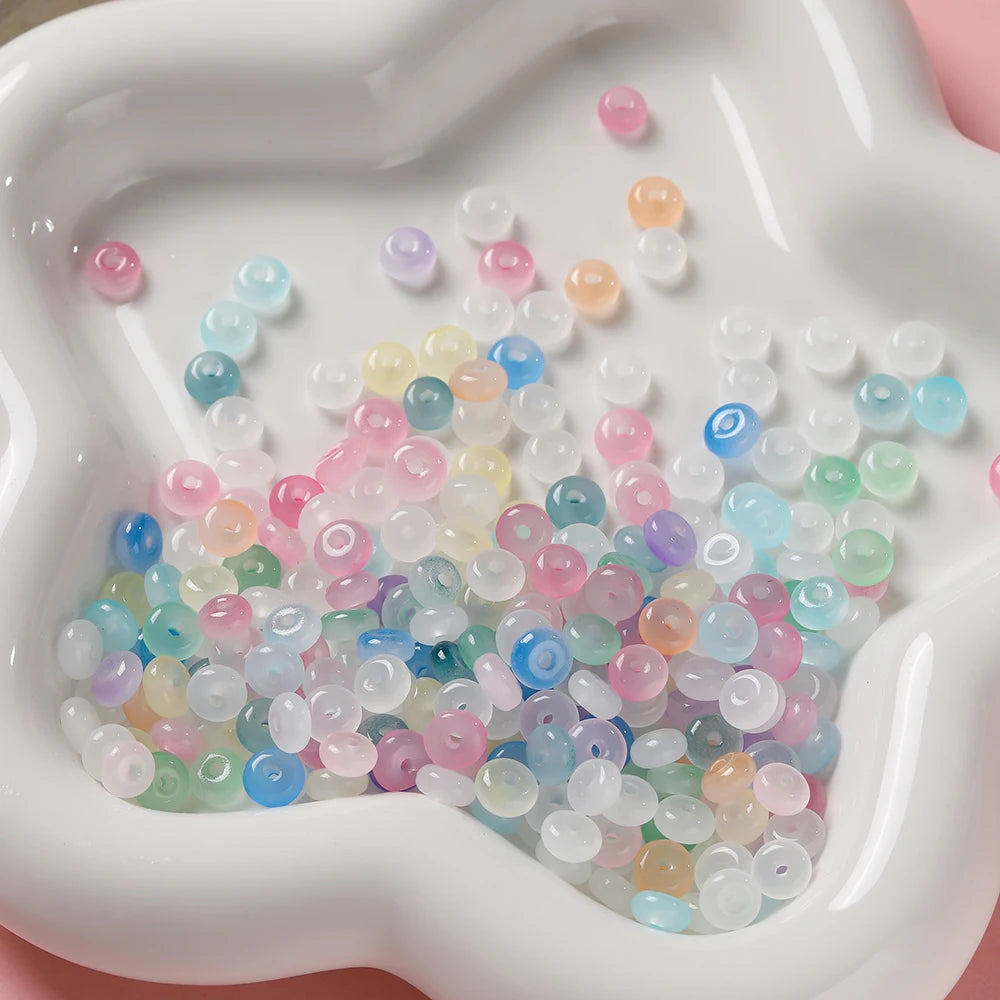 A close-up view of a white silicone mold filled with various colored glass spacer beads.