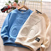 A light blue and cream cartoon bear pullover sweatshirt displayed on a hanger with a small toy car in the background.
