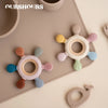 A collection of colorful, rudder-shaped silicone baby teethers with wooden rings arranged on a light surface.