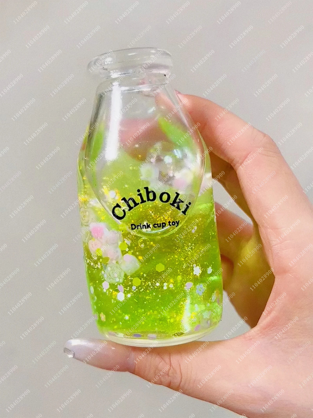 A hand holds a clear bottle of green liquid labeled Chiboki drink cup toy