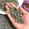 A hand holds a pile of natural crystal chips, including chalcopyrite and pyrite mineral decor.
