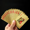 A hand holds a fan of gold glitter poker playing cards with red hearts and jacks.
