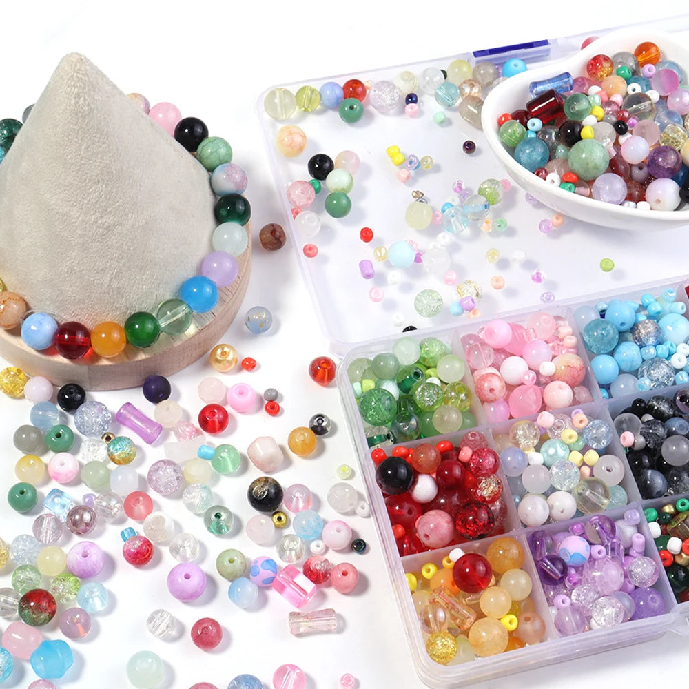 A variety of colorful glass beads in various shapes and sizes are displayed on a white surface.