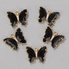 A set of gold-toned butterfly charm beads with black onyx and clear crystal accents for jewelry making.