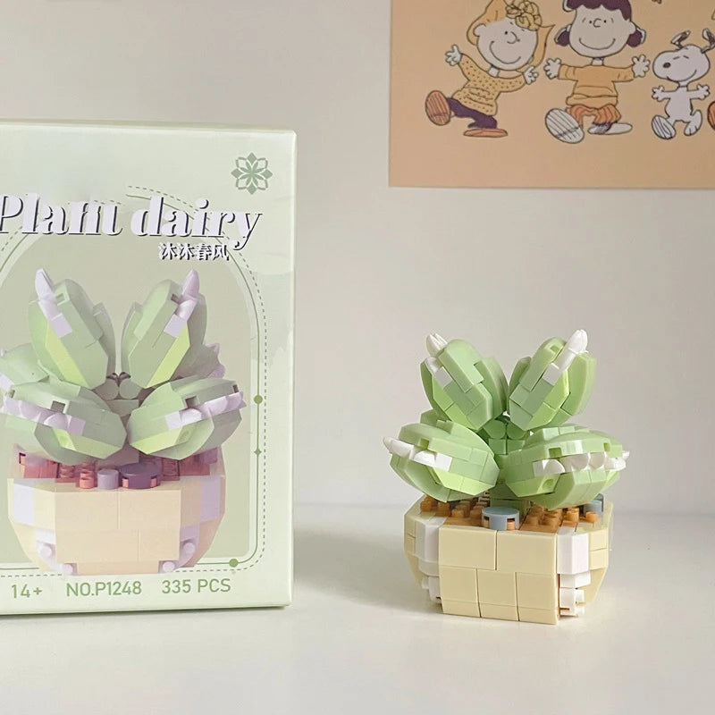 A miniature flower bouquet made of light green and pink building blocks displayed next to its packaging.