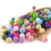 A collection of colorful silicone round beads in various shades of green, pink, yellow, blue, and purple arranged on a wooden