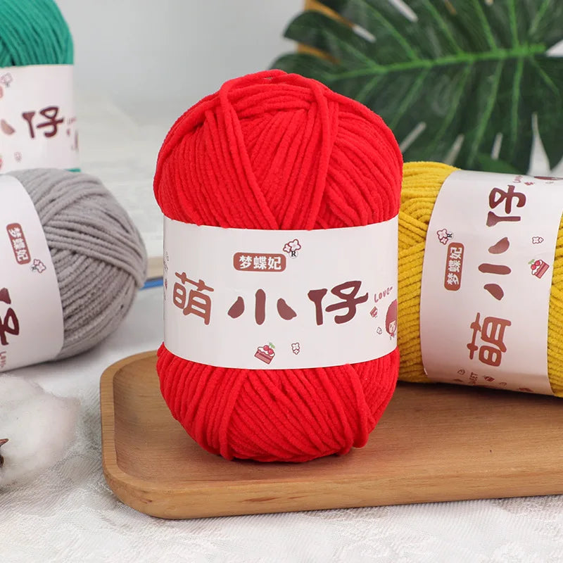 A bright red ball of soft chenille yarn is displayed next to a gray ball and a yellow ball, with labels in Chinese characters