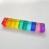 A row of colorful, translucent acrylic building blocks in a rainbow gradient.