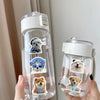 A hand holds a clear water bottle filled with water and decorated with waterproof cute animal stickers.