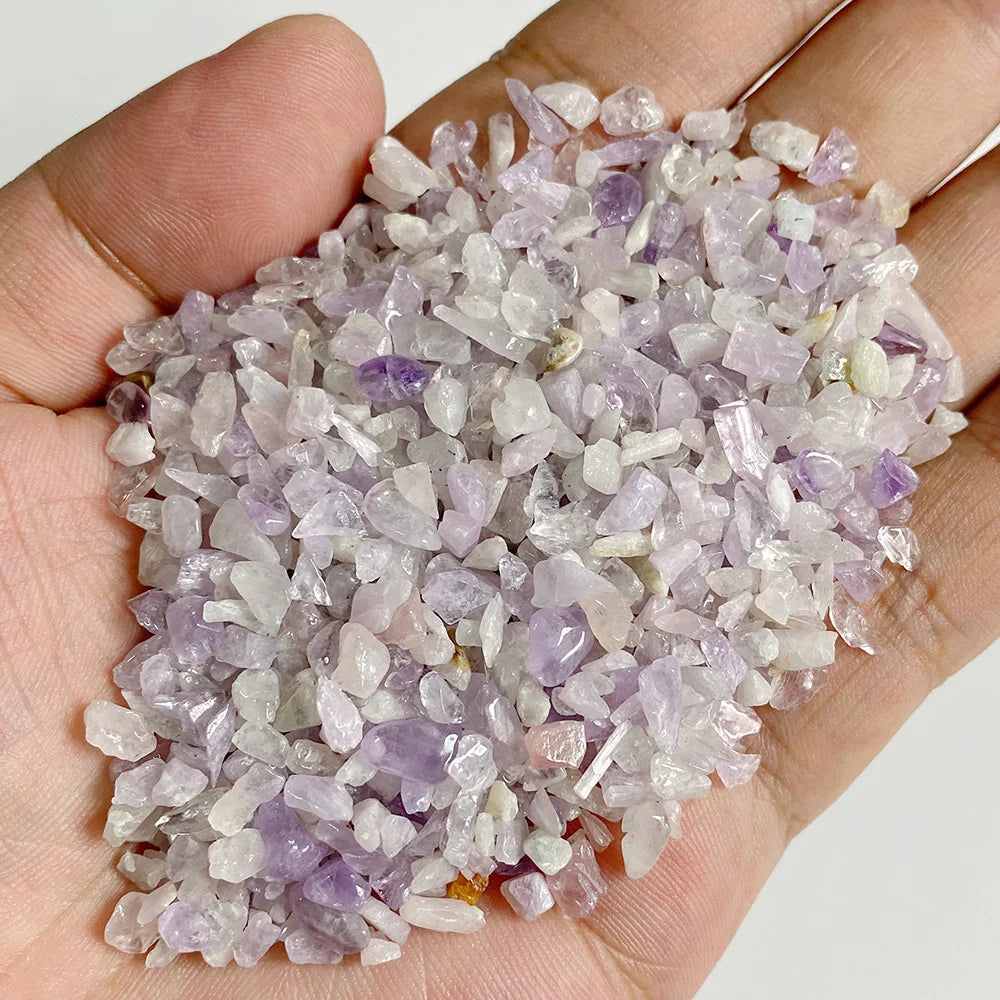 A hand holds a pile of light purple and clear quartz stone chips for jewelry making