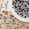 A plate filled with a large quantity of black and white acrylic alphabet and number beads for jewelry making