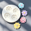 A collection of silicone daisy flower molds in various pastel colors, including blue, purple, pink, and yellow, displayed on 