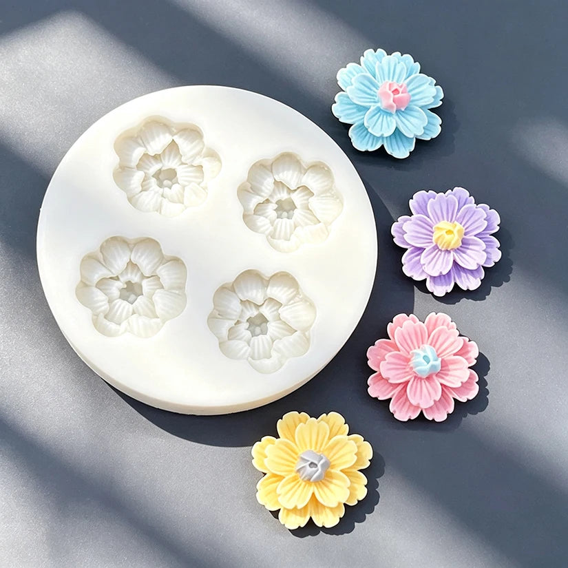 A collection of silicone daisy flower molds in various pastel colors, including blue, purple, pink, and yellow, displayed on 