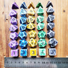 A set of complete polyhedral dice in various colors and shapes laid out on a wooden surface next to a ruler.