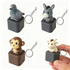 A set of animal clickers, including a gray duck, a gray donkey, and a brown monkey, with attached chains.