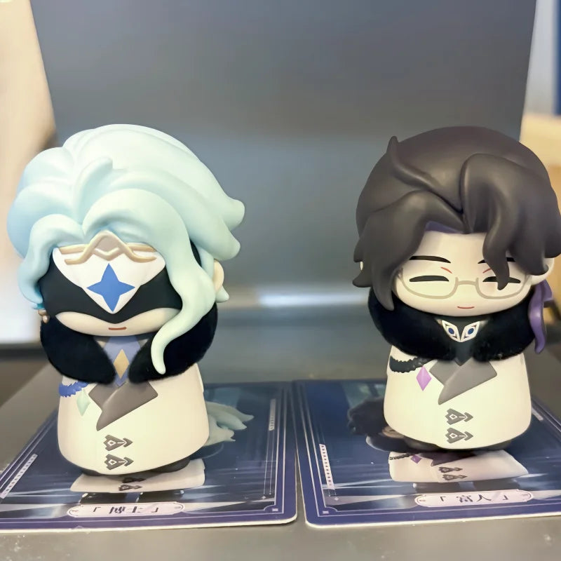 Two chibi figurines of Fatui Harbingers with light blue hair and dark hair, displayed in their blind box packaging.