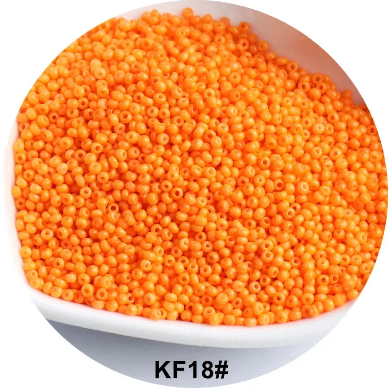 A pile of bright orange 1.5mm solid glass seed beads in a white dish.