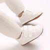 A pair of classic white soft-sole baby first walkers with knit socks shown from the side.