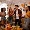 Four young adults are enthusiastically using inflatable microphones in a lively party setting.