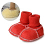 Pair of bright red suede baby booties with plush fur lining and white stitching