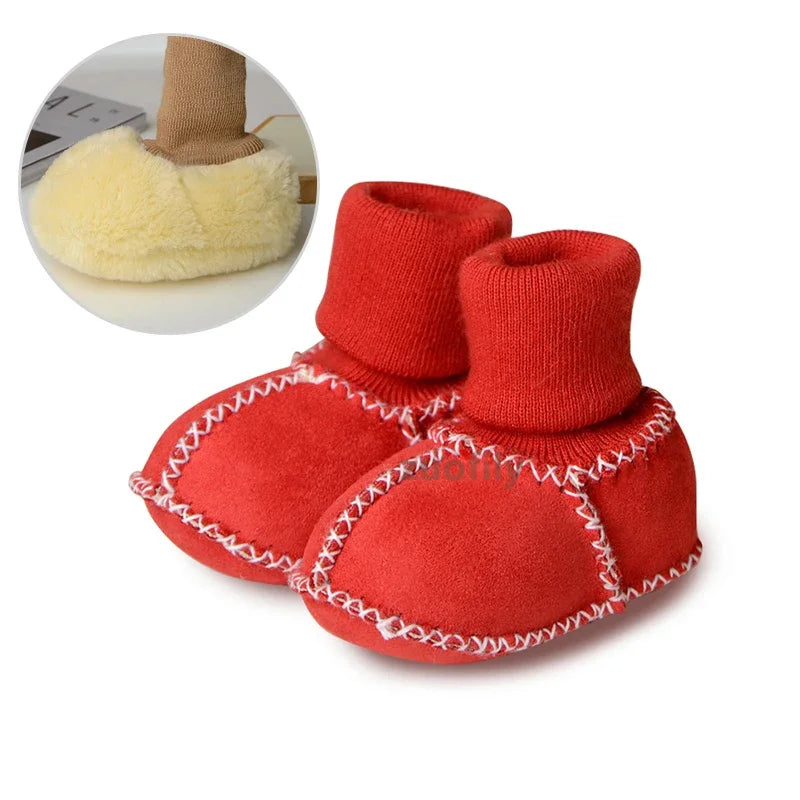 Pair of bright red suede baby booties with plush fur lining and white stitching