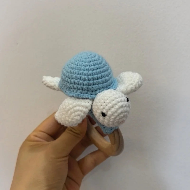 A handmade wooden baby rattle and teether ring shaped like an otter, featuring blue and white textured parts.