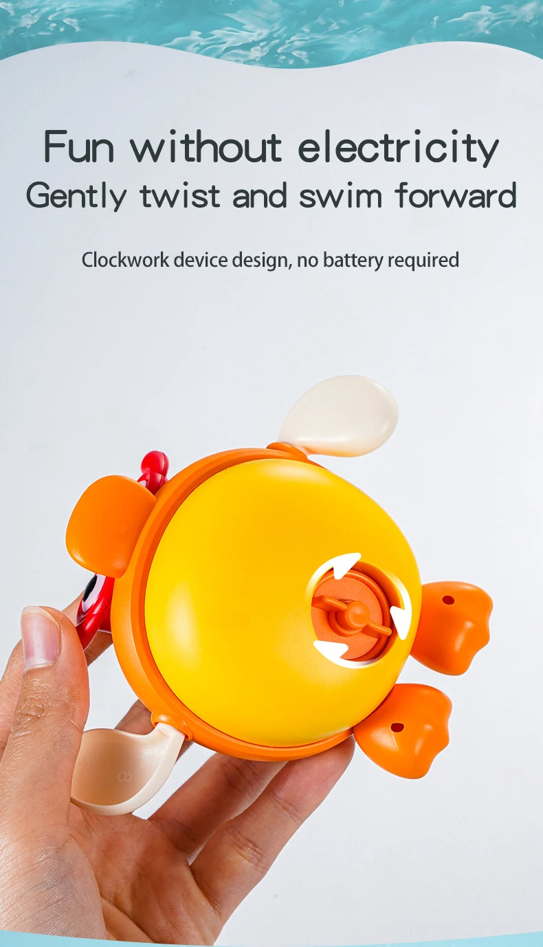 A hand holds a yellow wind-up swimming bath toy with orange accents, designed to twist and swim forward.