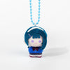 A small plush charm of an anime character with blue hair and purple eyes hanging from a light blue beaded necklace.