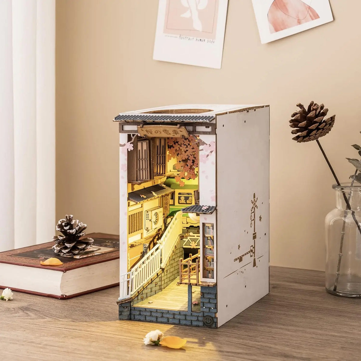 A miniature dollhouse kit resembling a traditional Japanese storefront is displayed on a wooden surface.