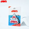 A pack of Jaws collectible enamel pins featuring shark designs and the movie title.